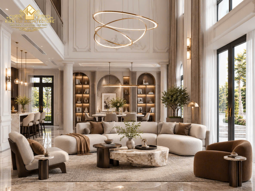 Phòng khách biệt thự thông tầng với sofa cong màu kem, bàn trà đá và đèn trần hình vòng.