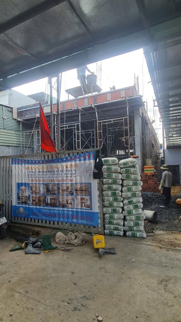 Công trình nhà ở đang thi công phần thô với giàn giáo mặt tiền và vật tư tập kết phía trước.