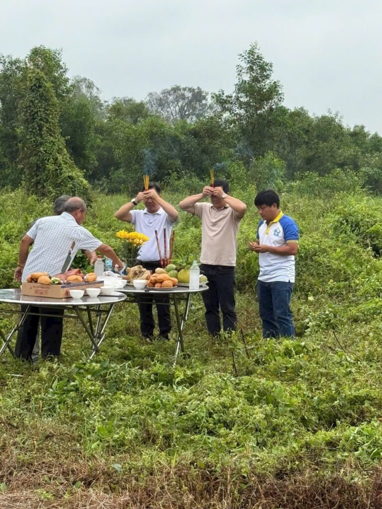 Nhóm người thực hiện nghi thức thắp hương bên bàn lễ ngoài trời tại khu đất chuẩn bị xây dựng.